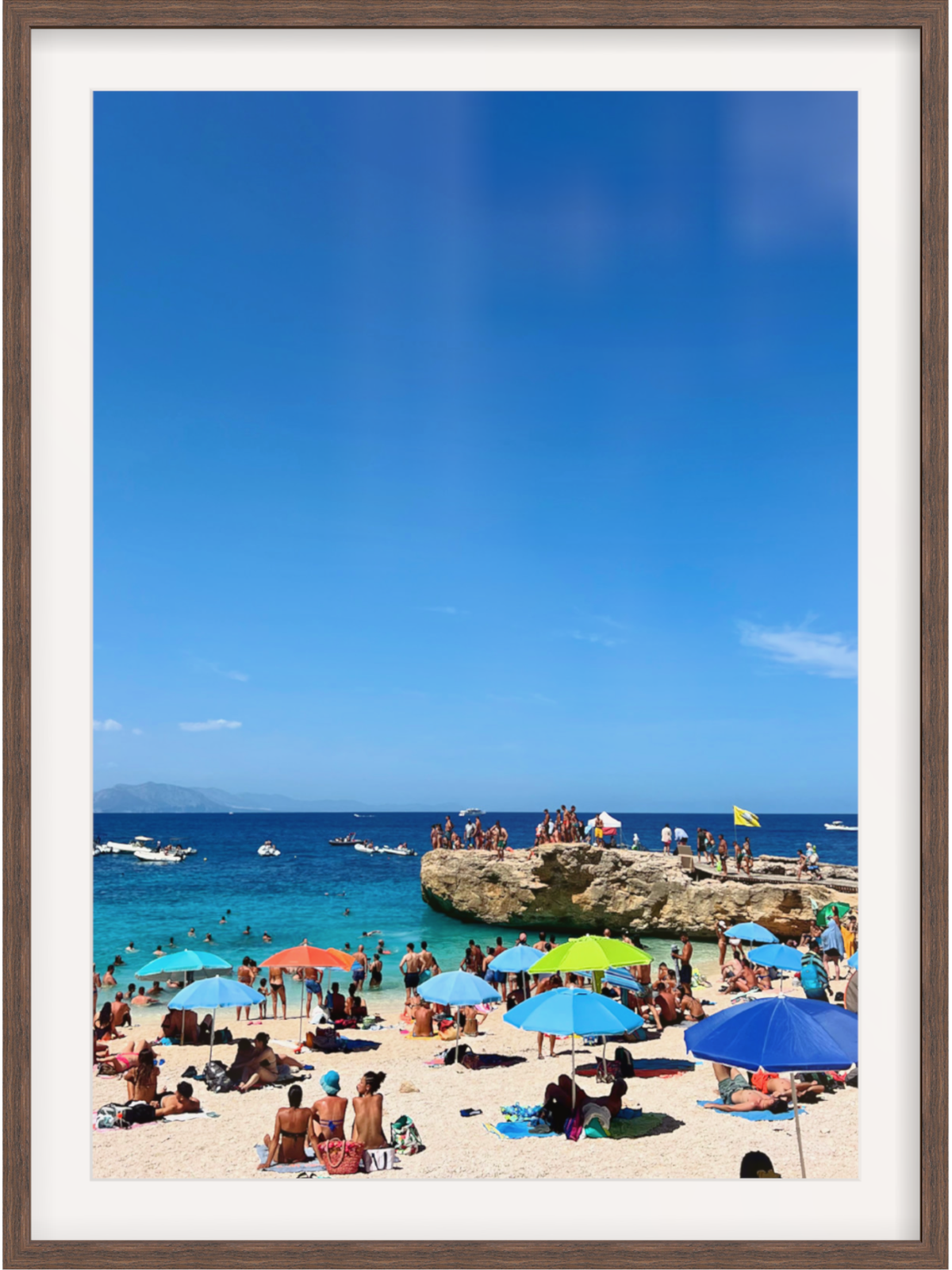 Beach scene with people under colorful umbrellas and a clear blue sky.