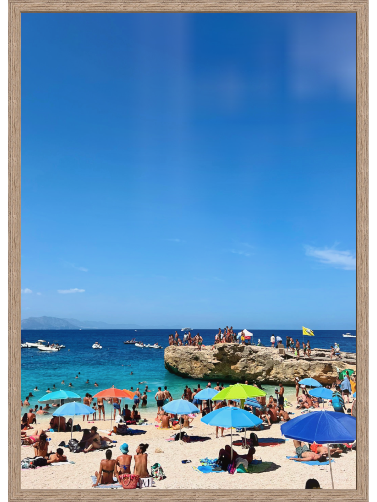 Beach scene with people, umbrellas, and a clear blue sky.
