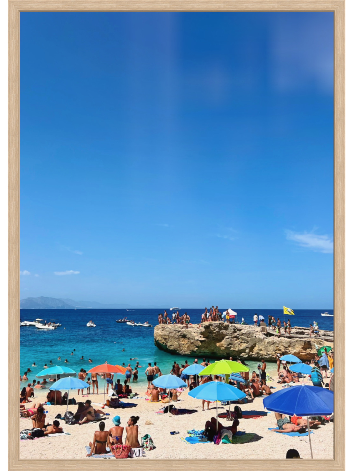 Beach scene with people, colorful umbrellas, and a clear blue sky.