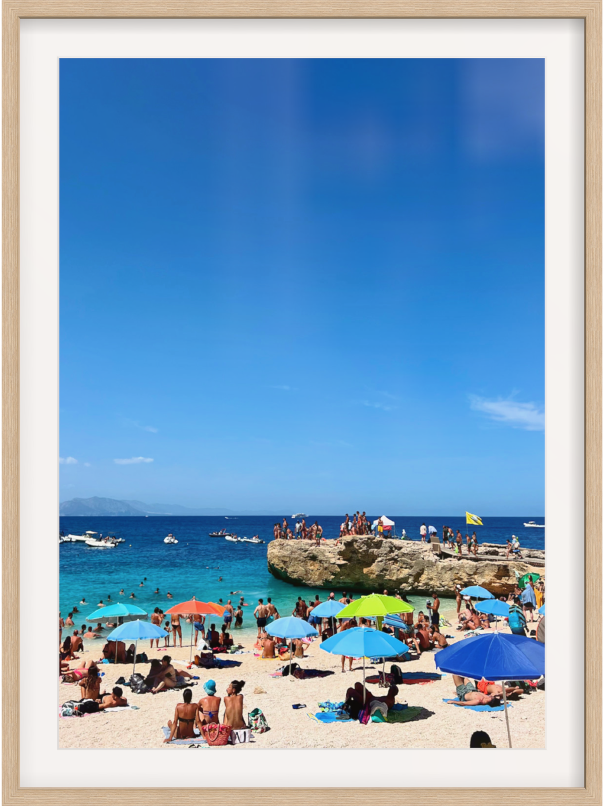 Beach scene with people under colorful umbrellas and a clear blue sky.