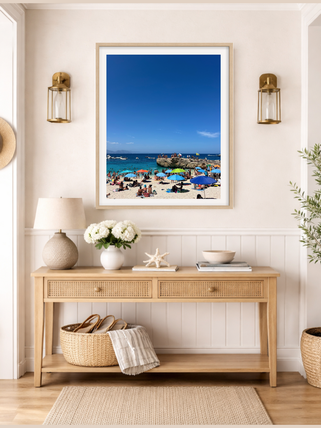 Framed beach scene above a wooden console table with decorative items.