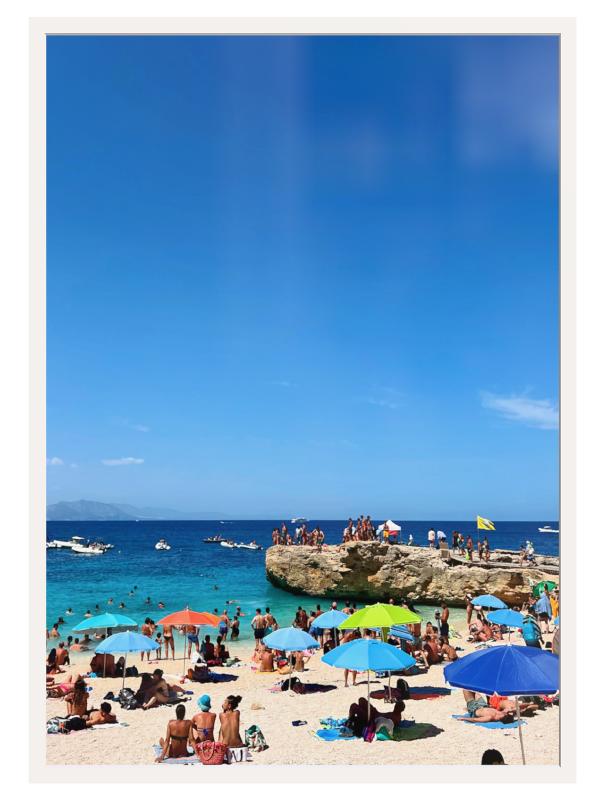 Beach scene with colorful umbrellas and people under a clear blue sky.