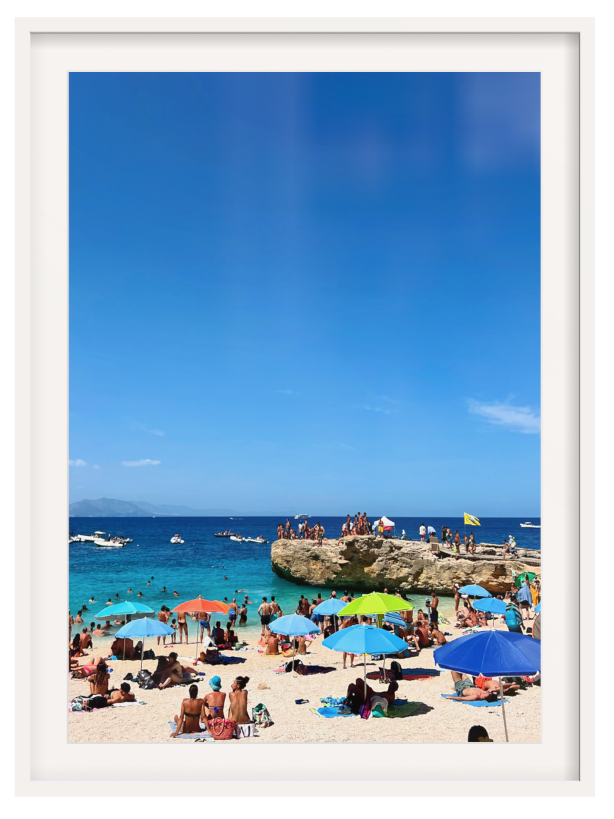 Beach scene with people under colorful umbrellas and a clear blue sky.