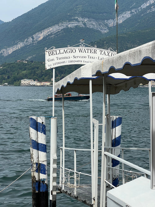 Borderless Bellagio jetty art print highlighting worn blue and white striped wooden pilings