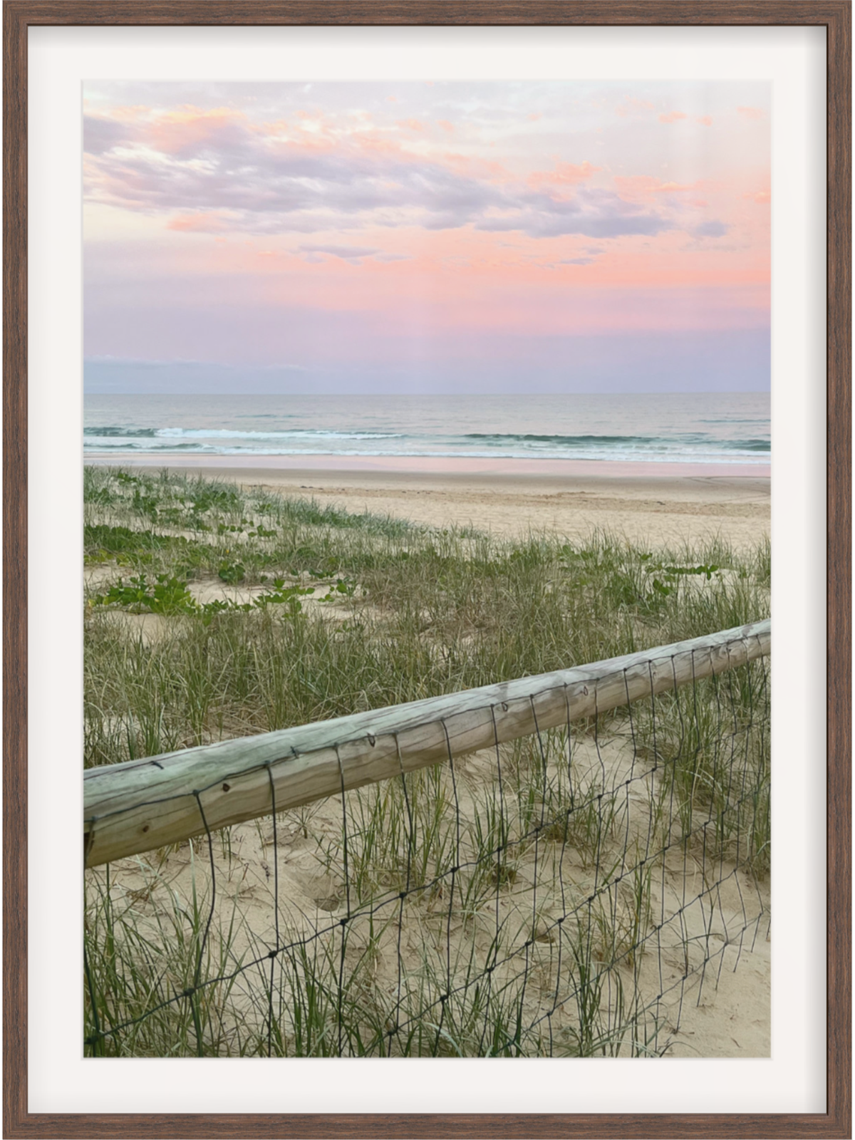 Dark brown wood framed coastal print with white mat and pastel clouds