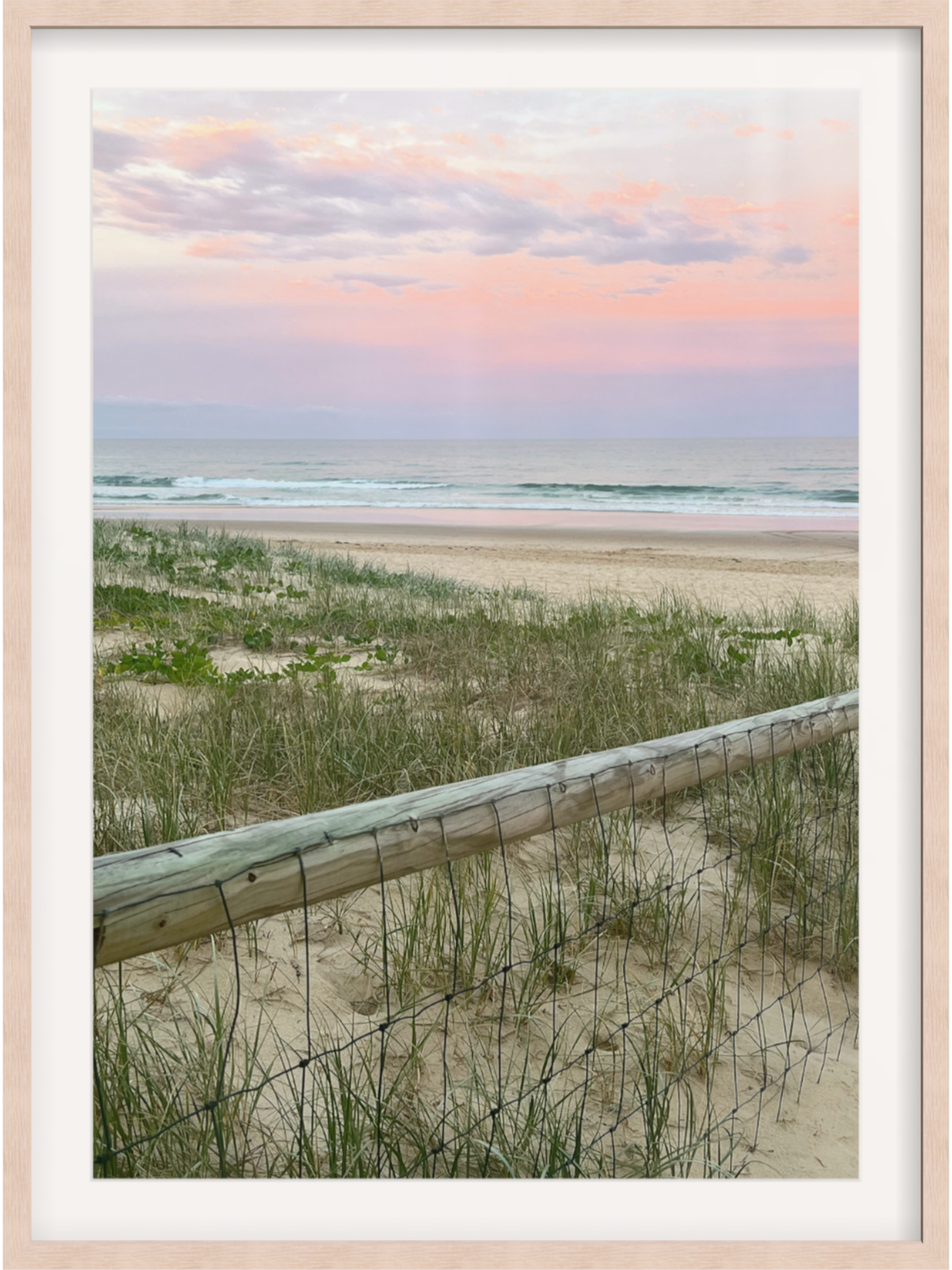 Natural light wood framed coastal print with wide white mat and sunset