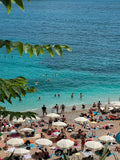 Beach scene with people, umbrellas, and clear blue water