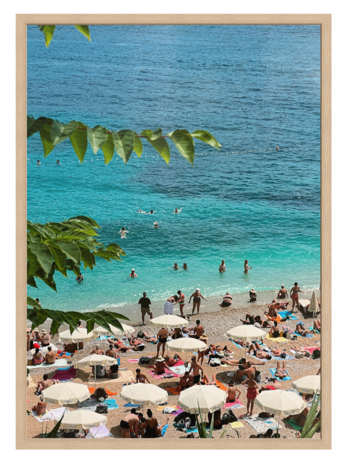 Beach scene with people, umbrellas, and clear blue water framed by green leaves. Banje Beach leaf oak frame