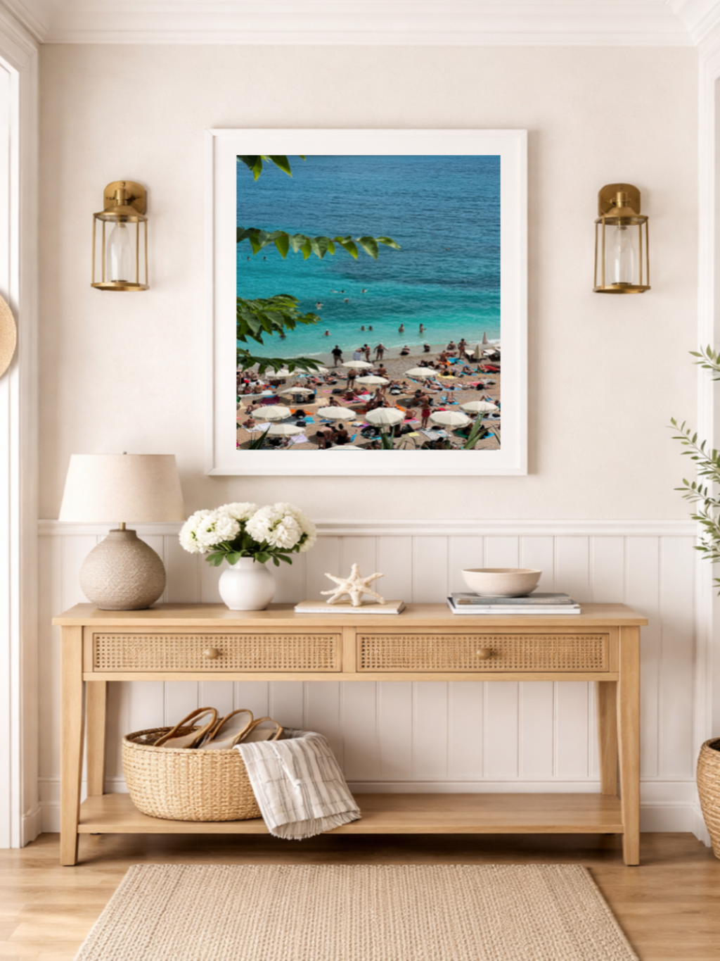 Framed beach scene print above a wooden console table with decorative items.