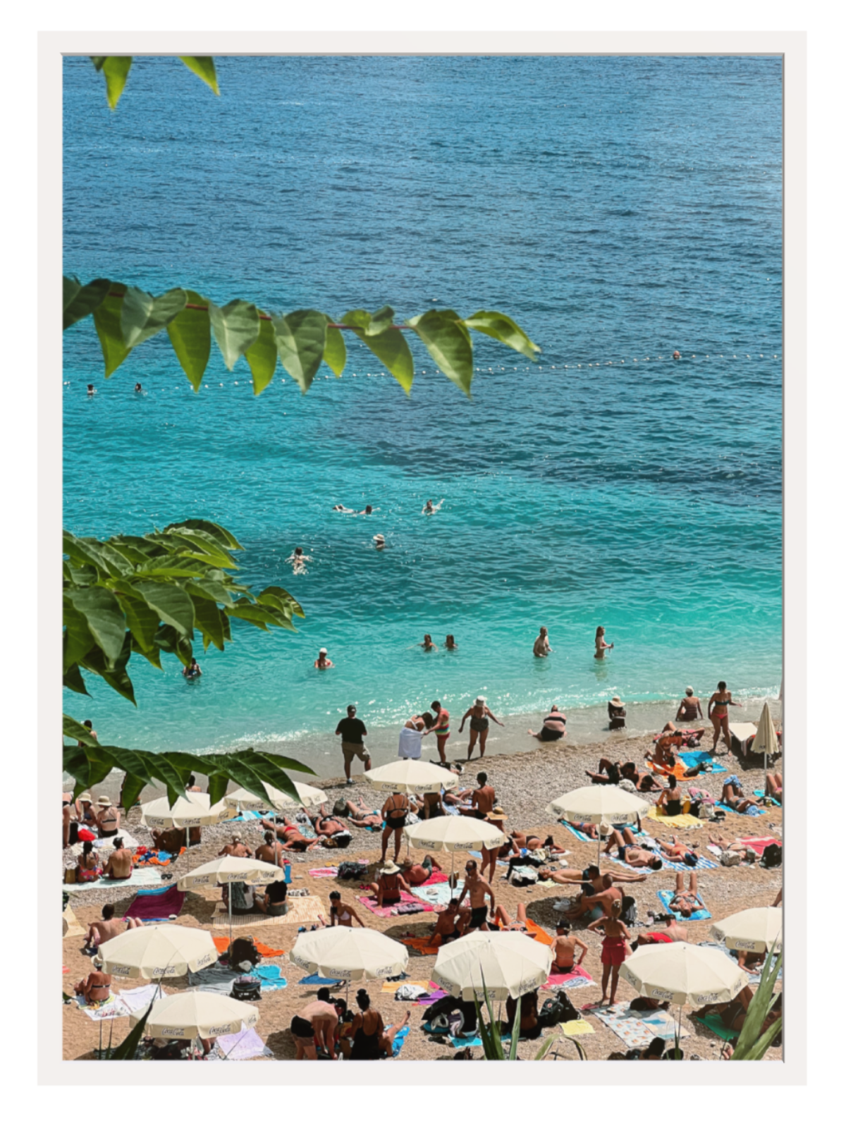 Beach scene with people, umbrellas, and clear blue water. white frame