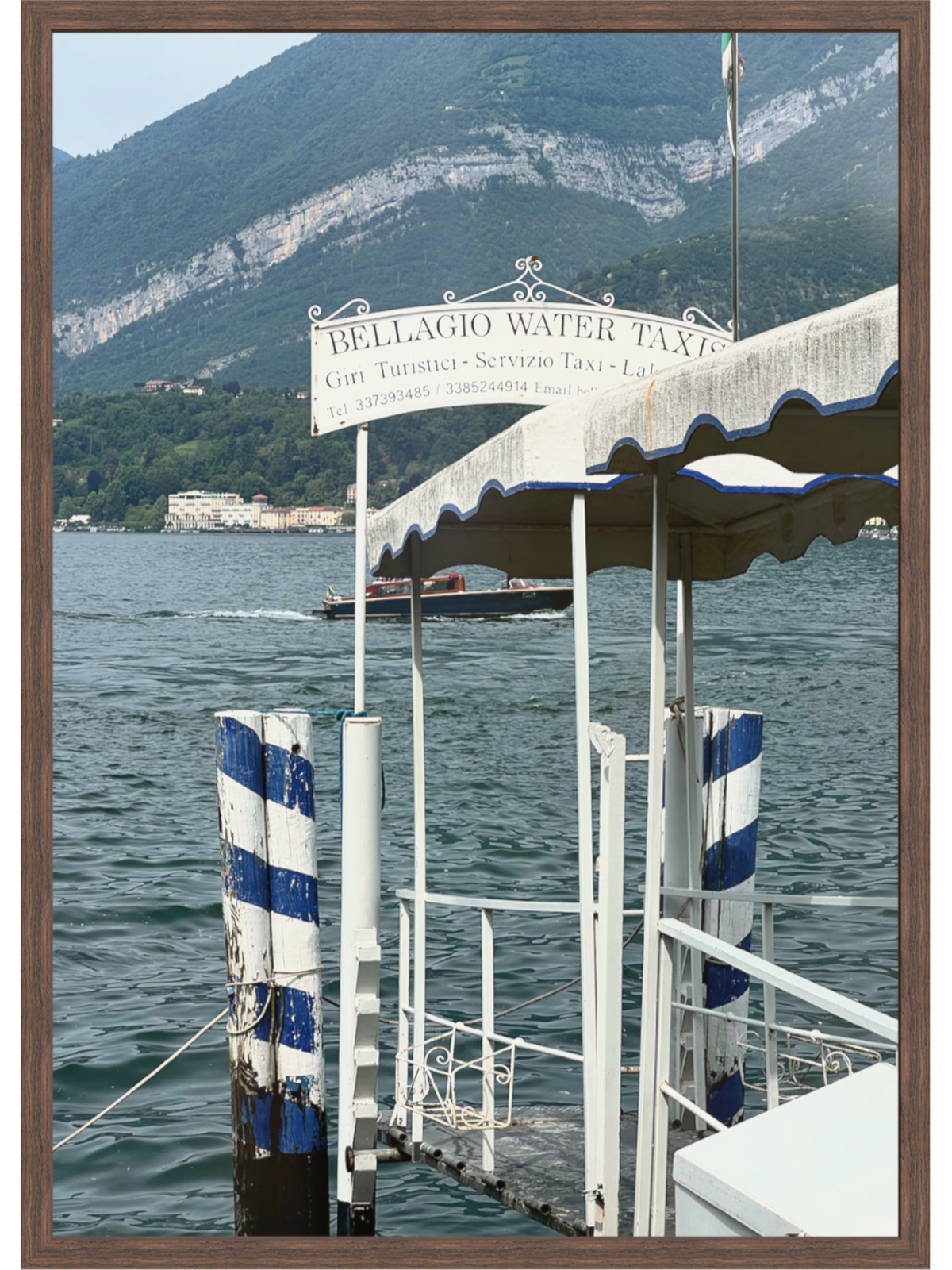 Dark brown framed Bellagio jetty print showing exposed rock faces and deep green-blue lake water