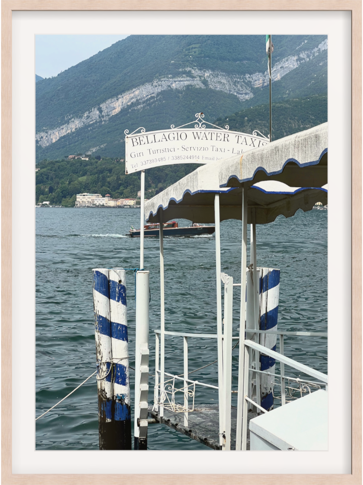 Bellagio waterfront print with rope-tied piling and ornate water taxi sign in light wood frame