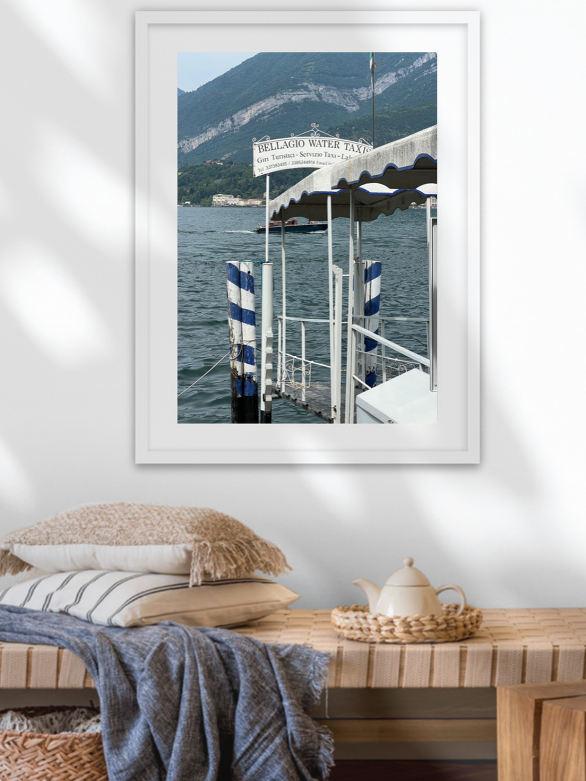 White framed Bellagio art print styled with woven bench and textured throw for cozy living room