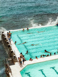People swimming in a pool with ocean water in the background