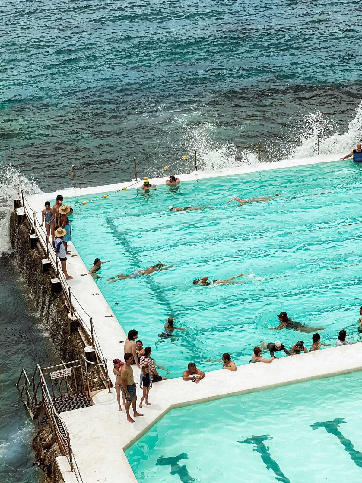 People swimming in a pool with ocean water in the background