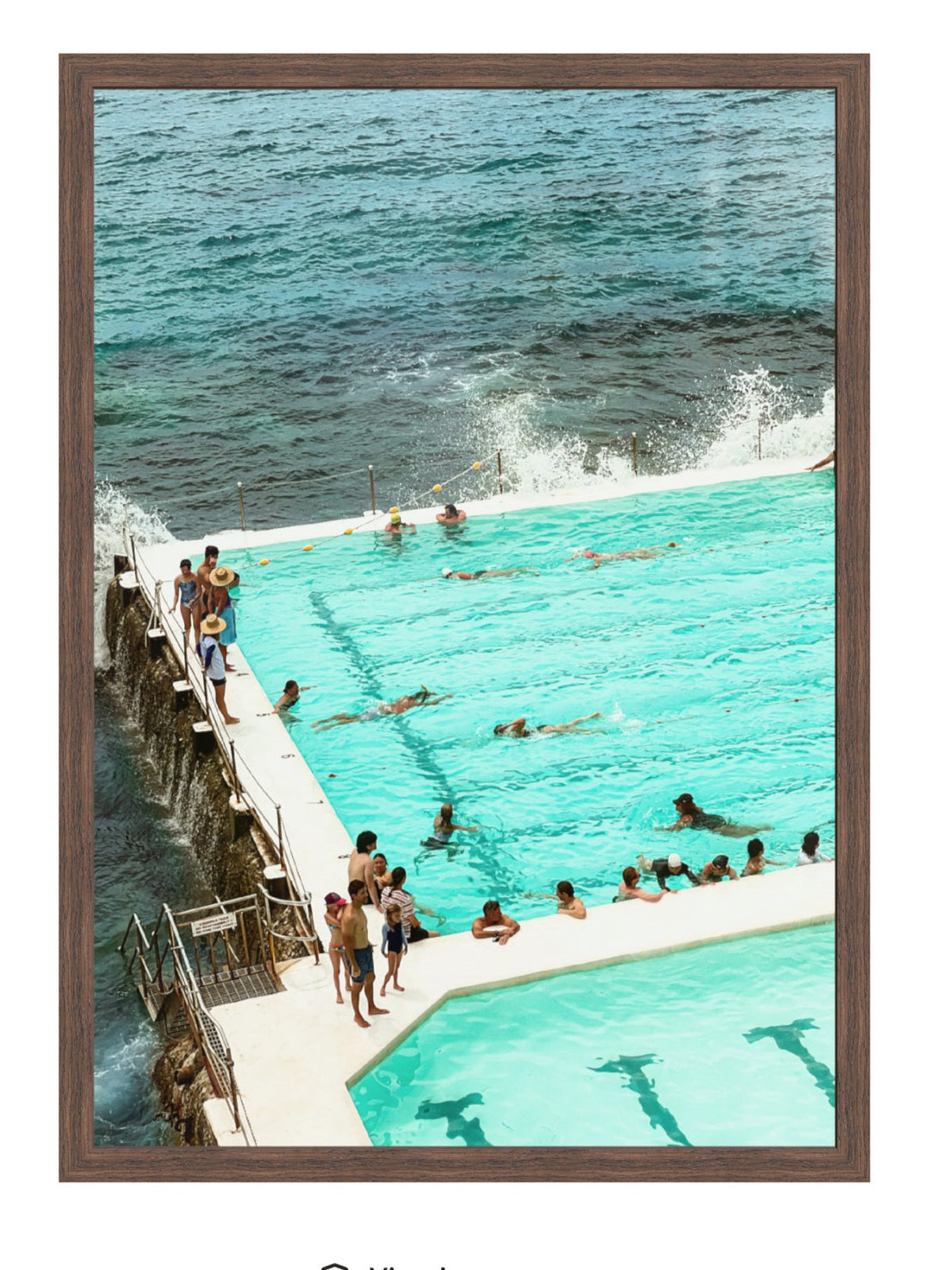 People enjoying a pool by the ocean with a wooden frame.