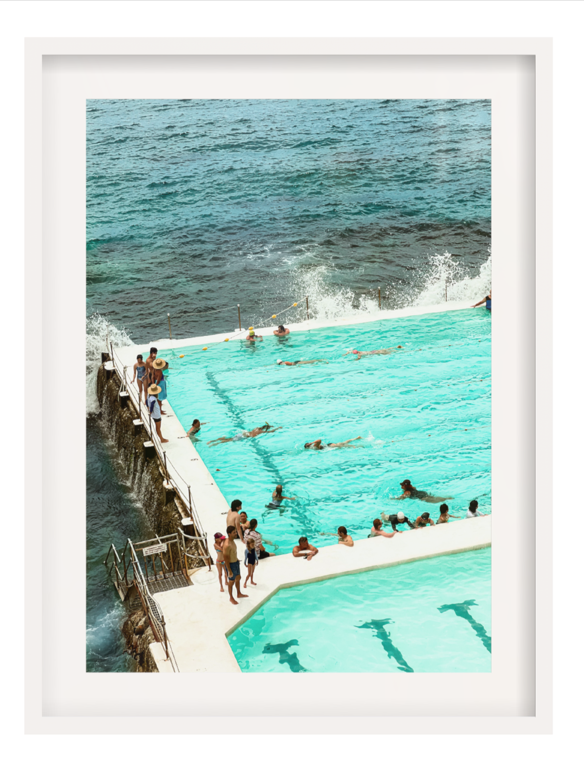 People enjoying a pool by the ocean with a white frame.