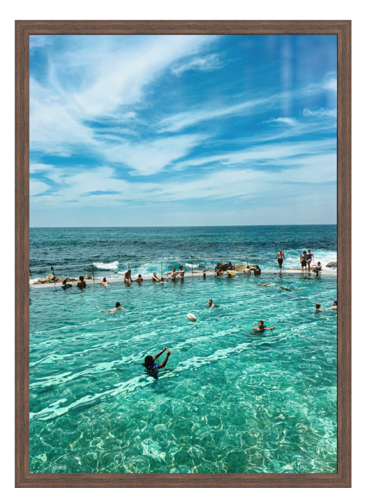 People enjoying a pool with clear blue water and a blue sky.