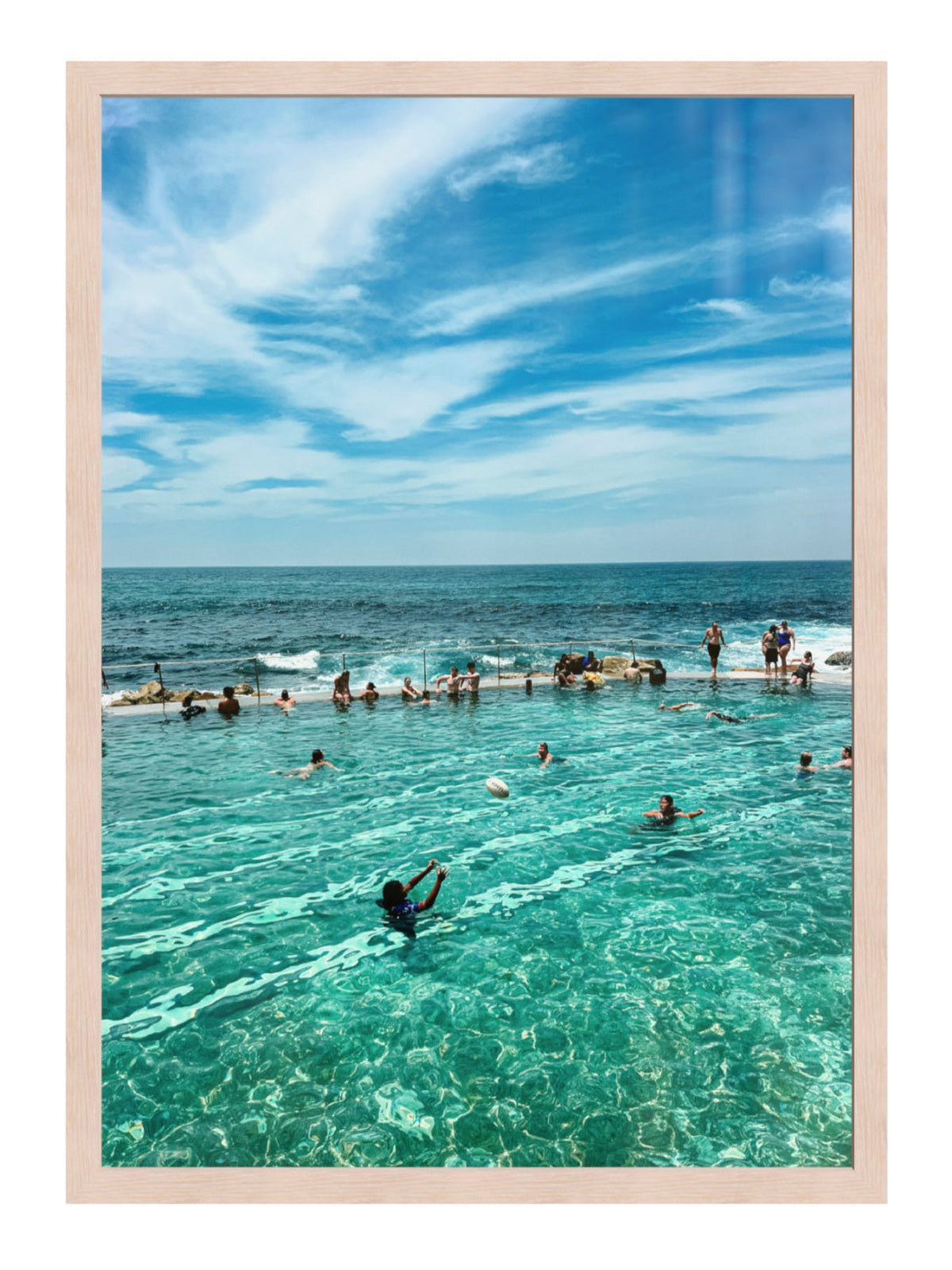 People swimming in a pool with ocean view under a blue sky