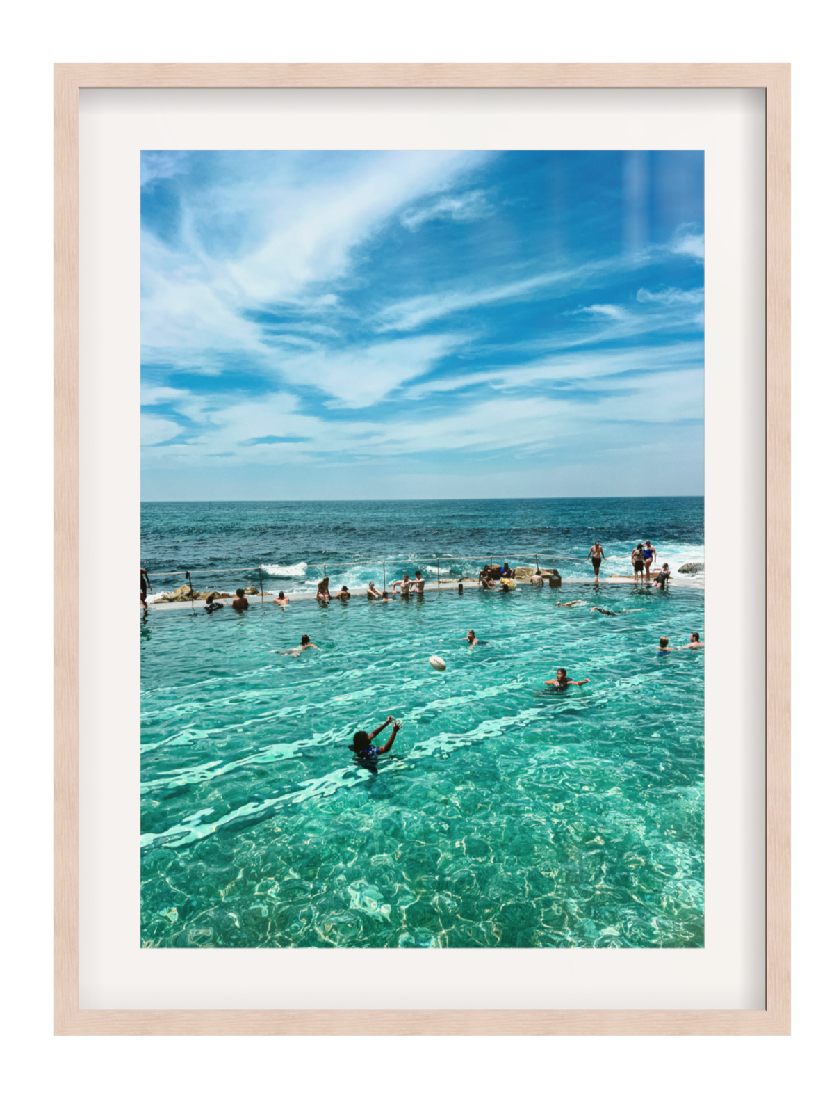 People enjoying a pool by the ocean with a clear blue sky.