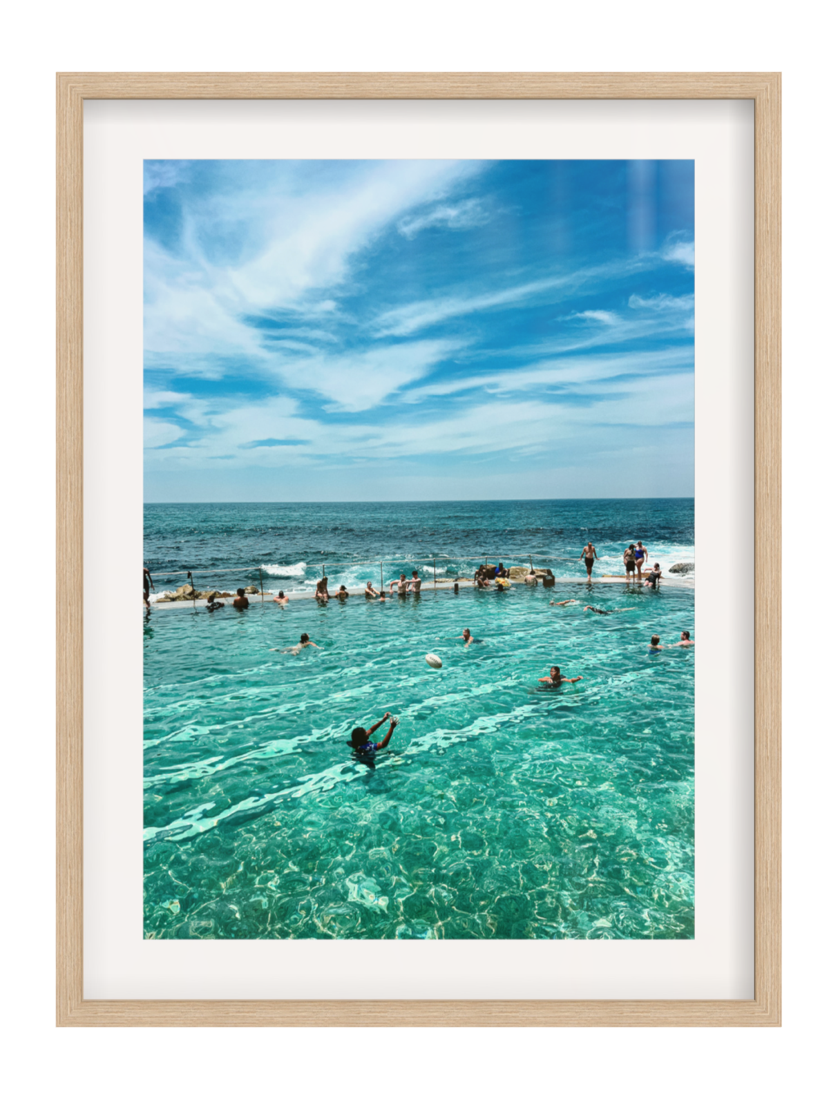 Framed photograph of a pool with people enjoying the water, set against a blue sky and ocean.