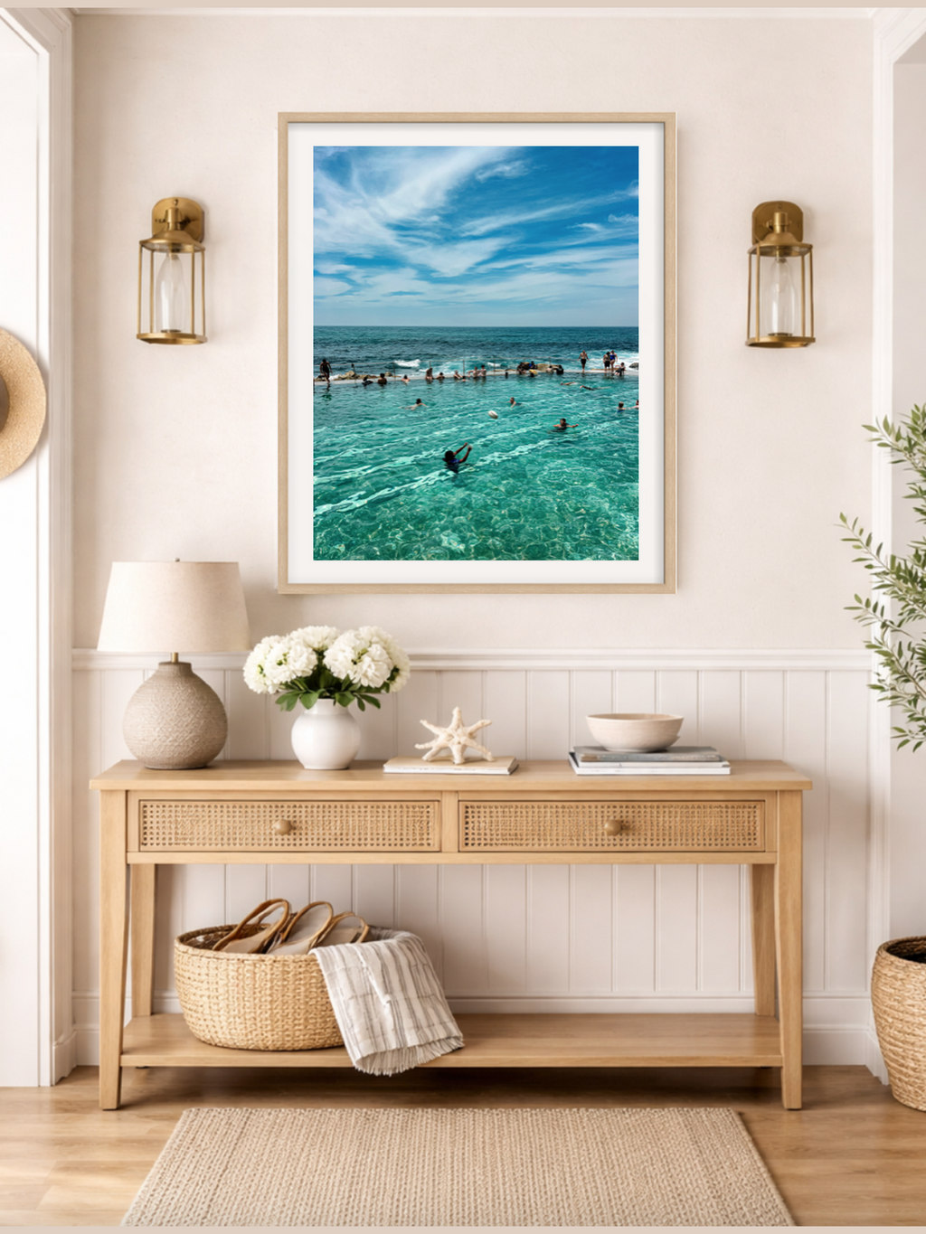 Framed beach scene above a wooden console table with decorative items.