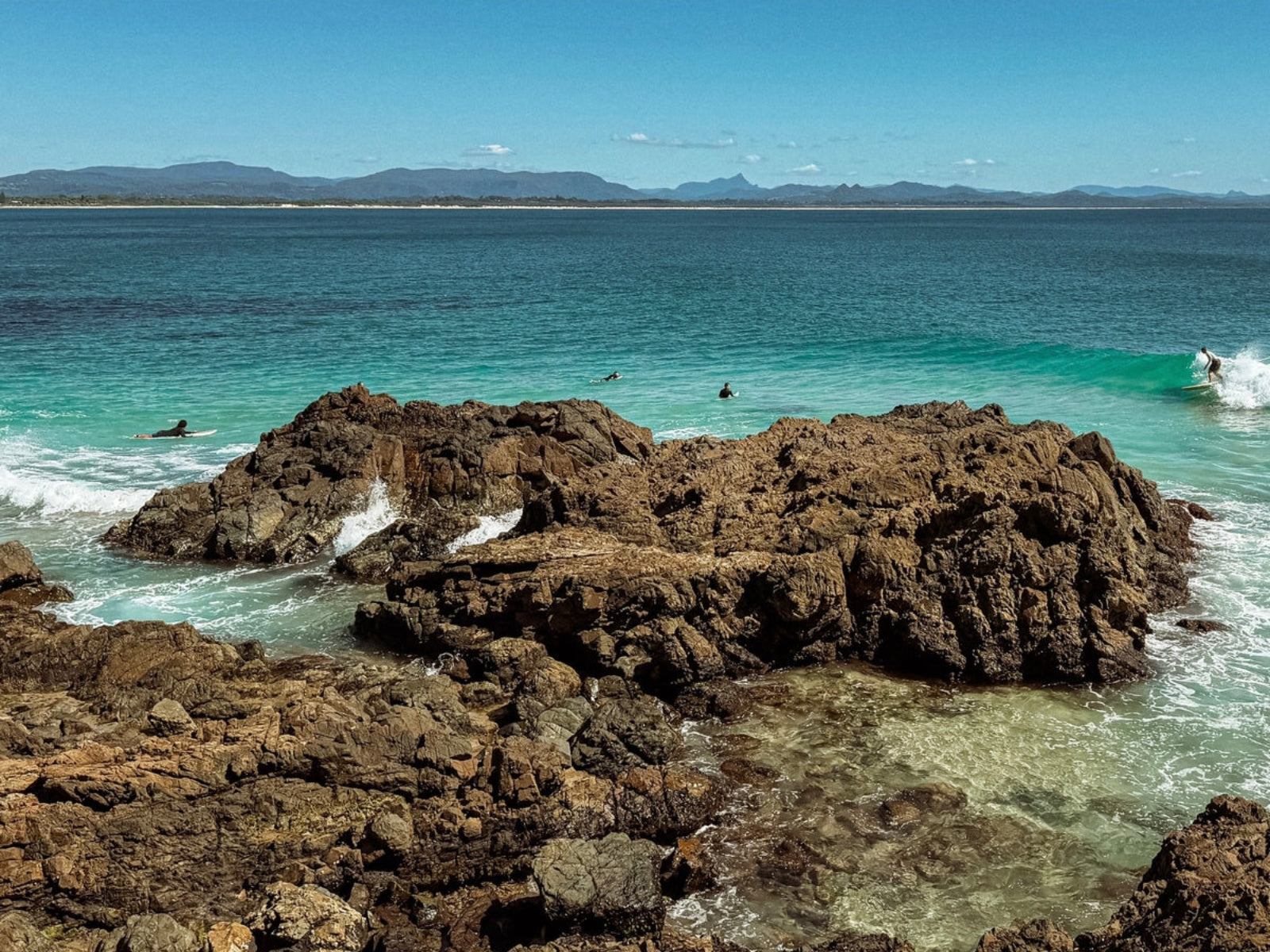 Rocks in a body of water with mountains in the distance