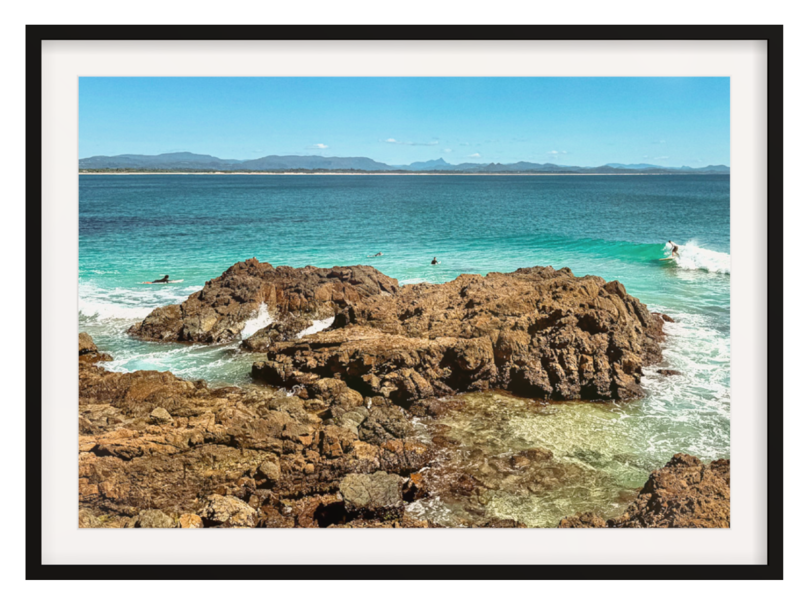 Framed photograph of a rocky coastline with clear blue water.