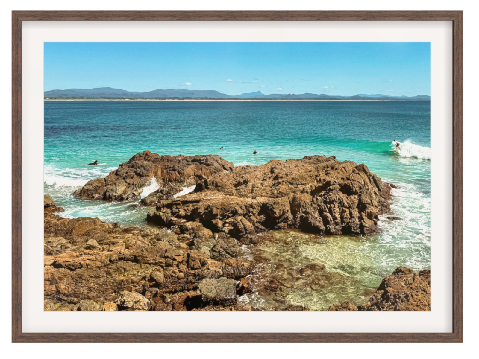 Framed photograph of a rocky coastline with clear blue water and distant mountains.