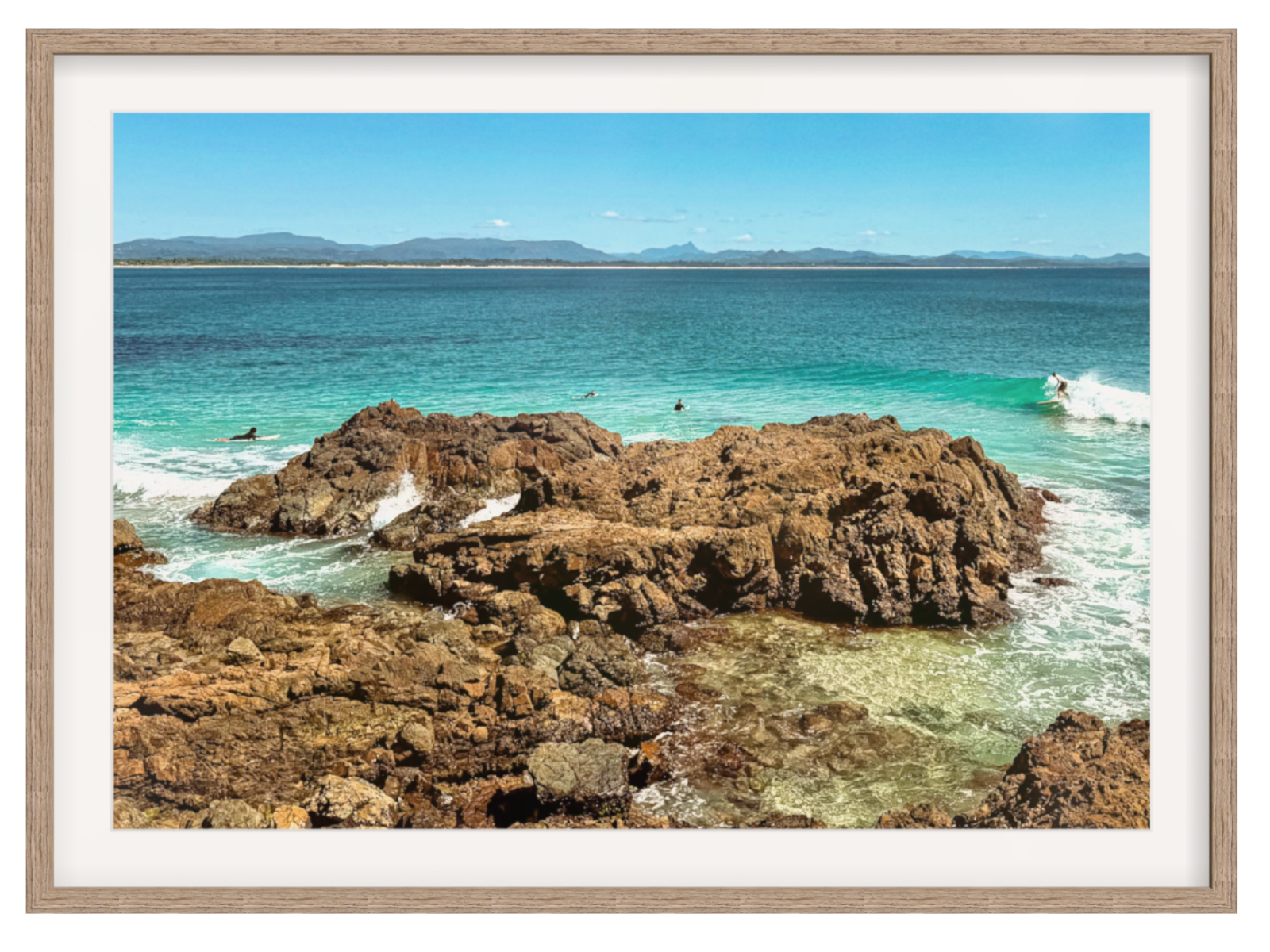 Framed photograph of a rocky coastline with clear blue water.