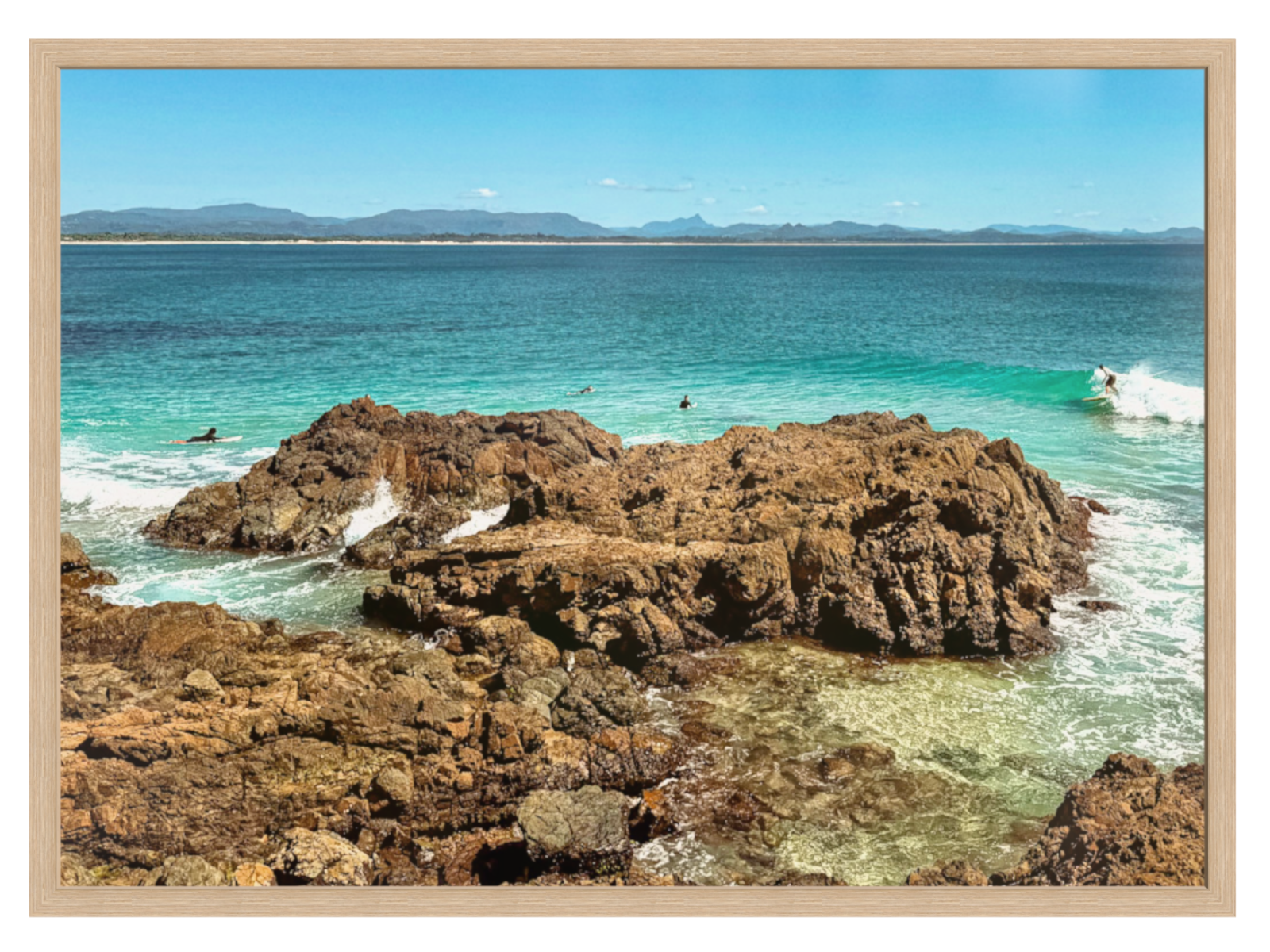 Rocks in a body of water with a clear blue sky