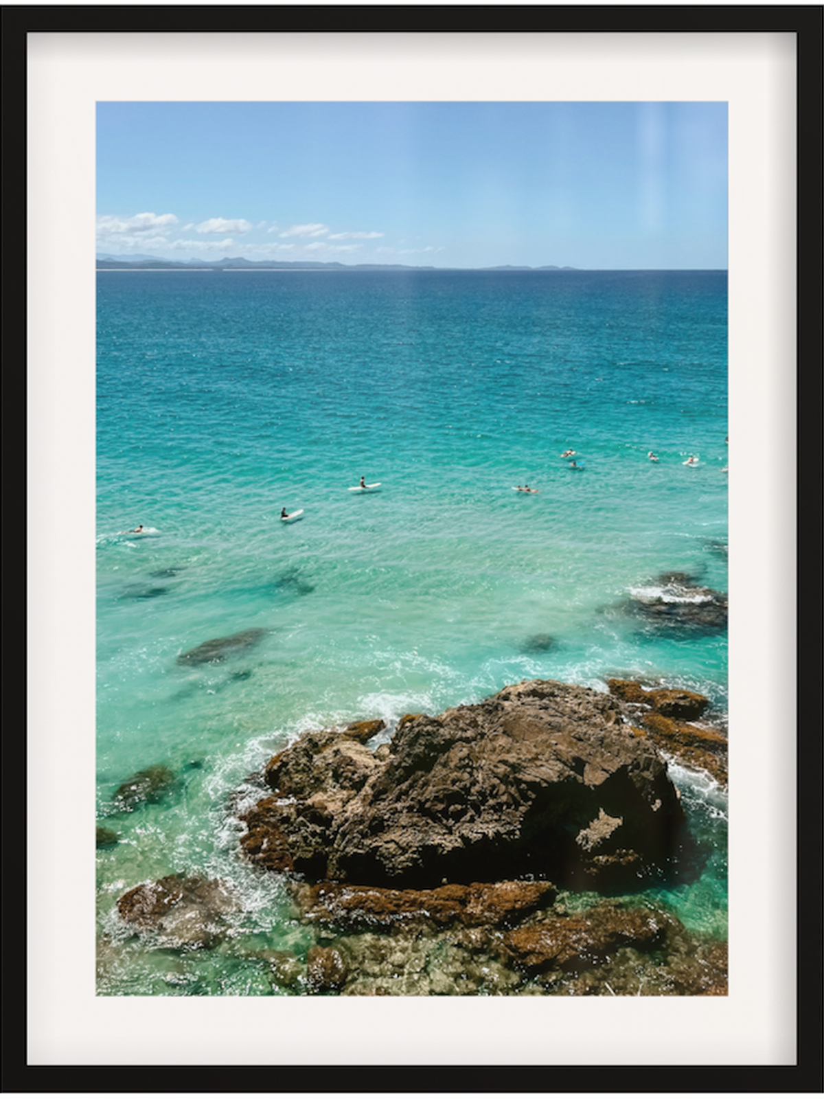 Framed photograph of a coastal scene with clear blue water and rocks.