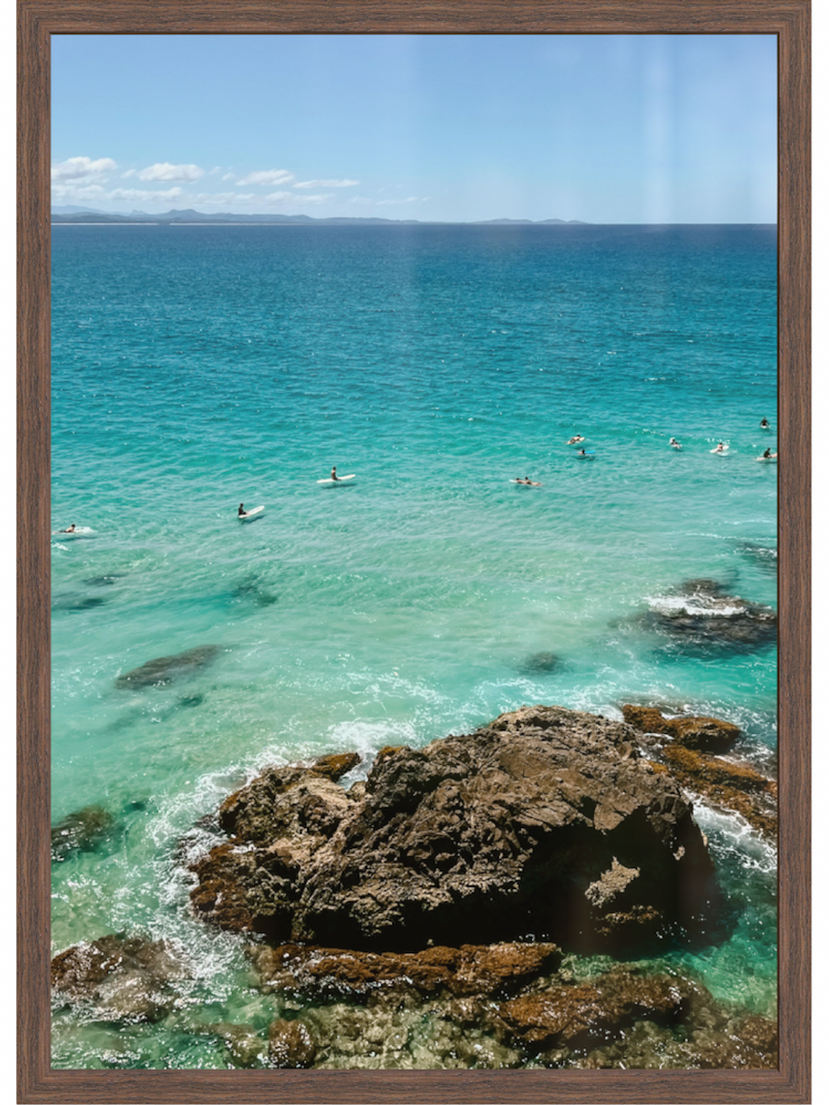 Ocean scene with people swimming and rocks, framed with a brown border