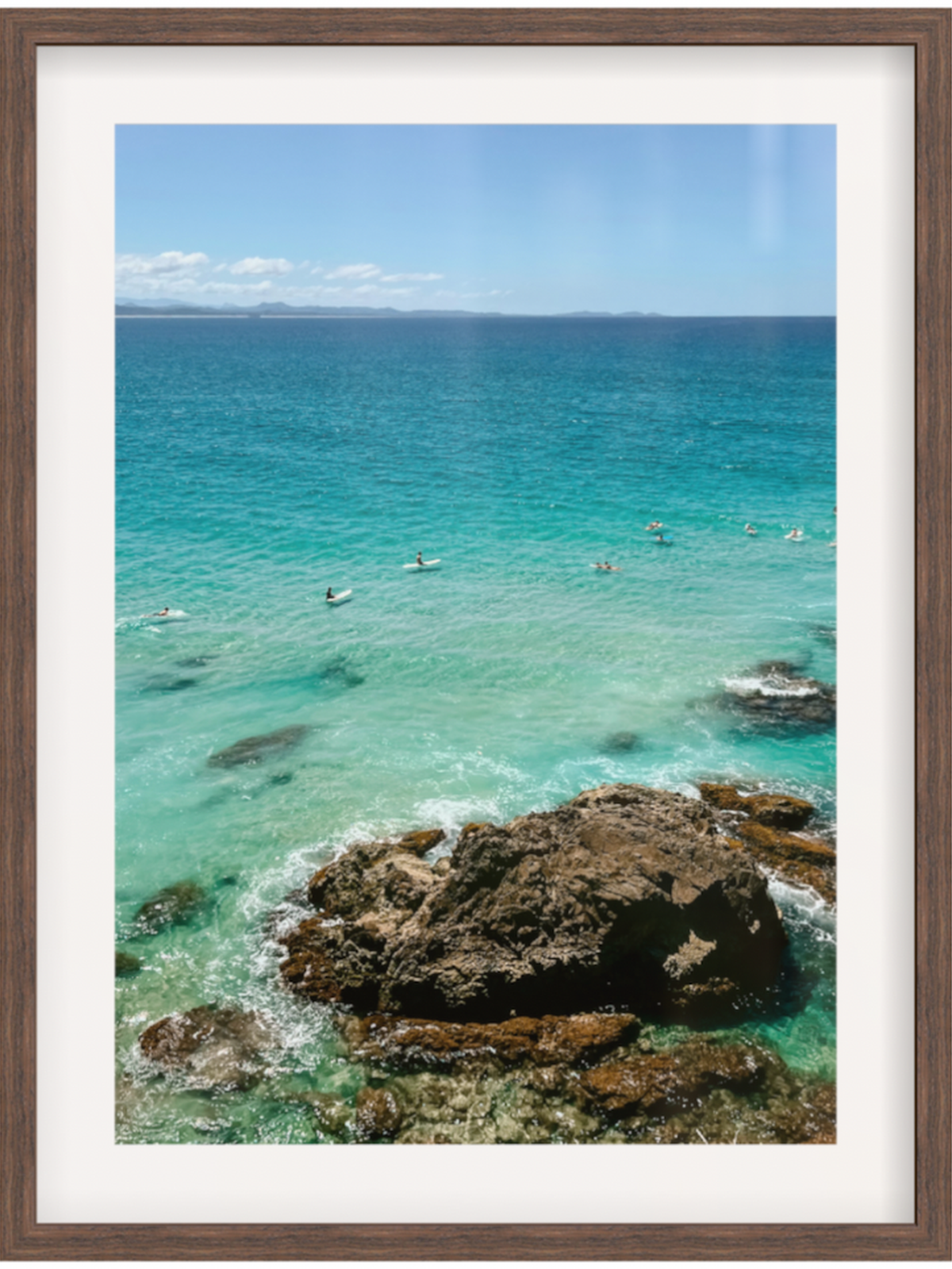 Framed photograph of a coastal scene with clear blue water and rocky shoreline.