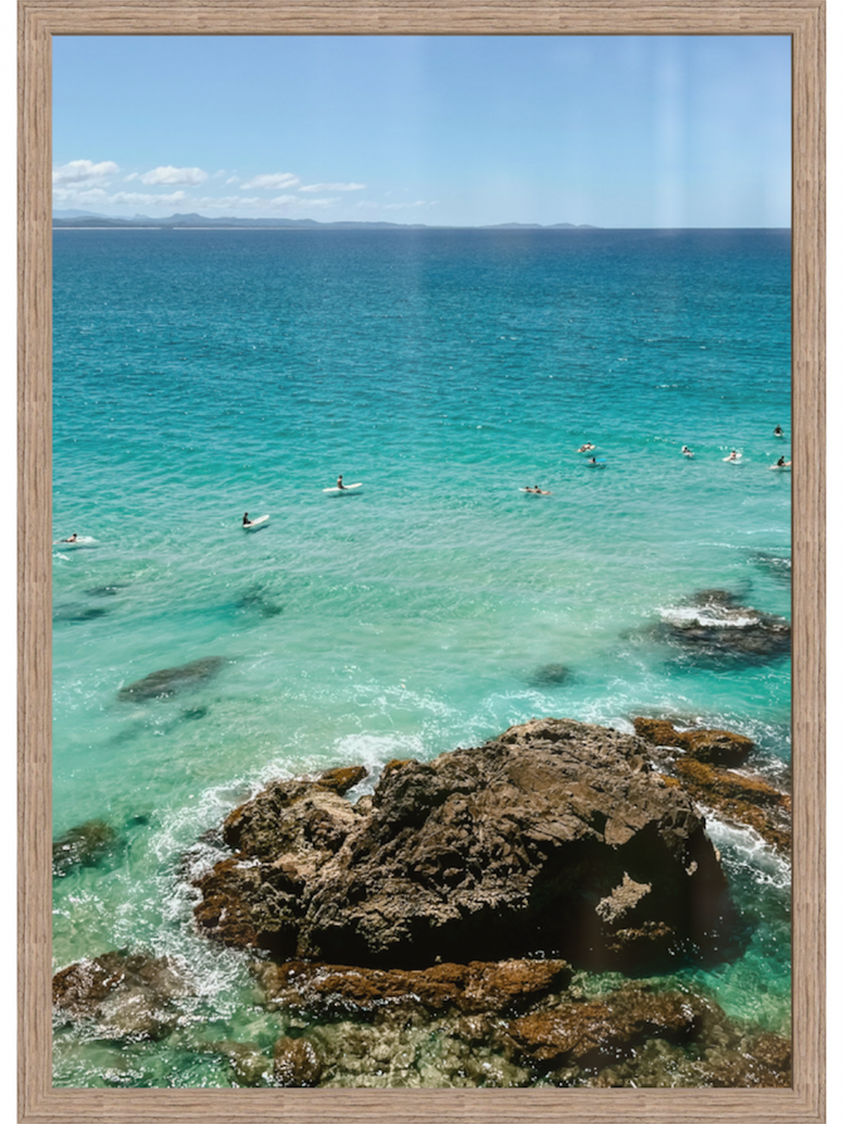 Ocean scene with clear blue water and rocky shoreline, framed like a picture.