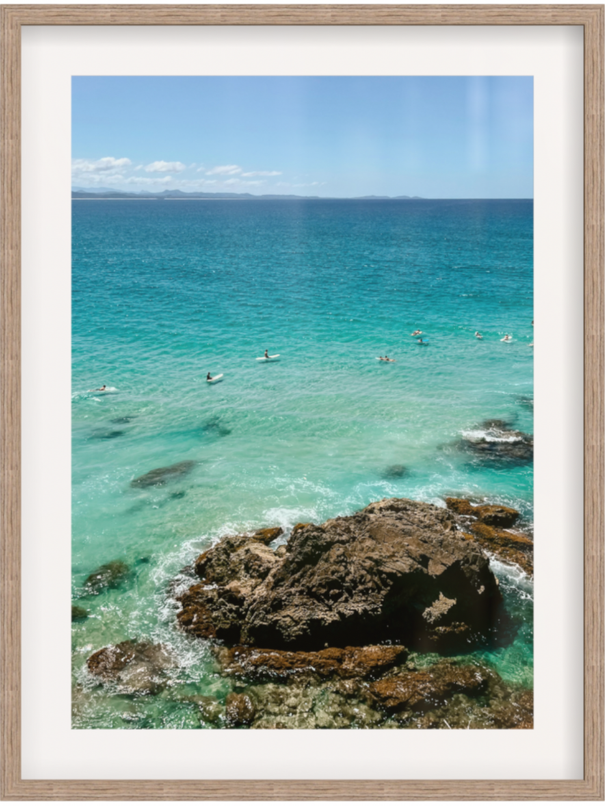Framed photograph of a coastal scene with clear blue water and rocky shoreline.