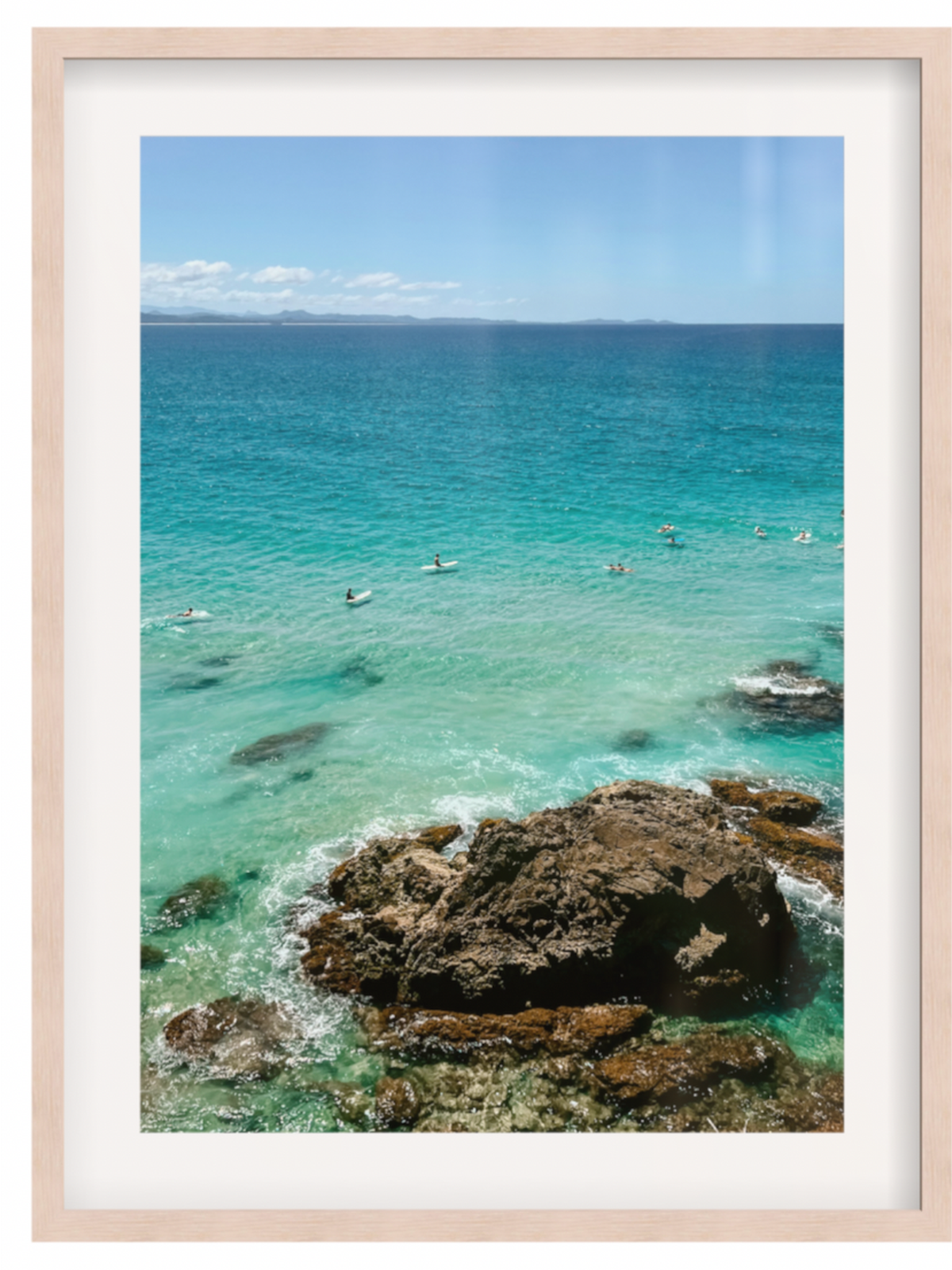 Framed photograph of a coastal scene with clear blue water and rocks.