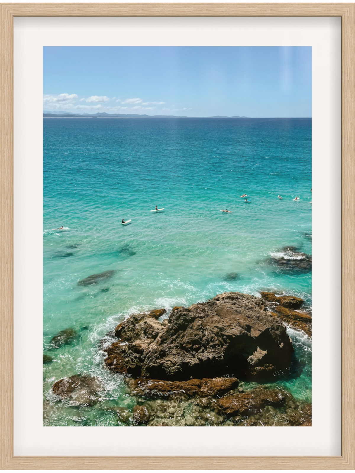 Framed photograph of a coastal scene with clear blue water and rocky outcrops.