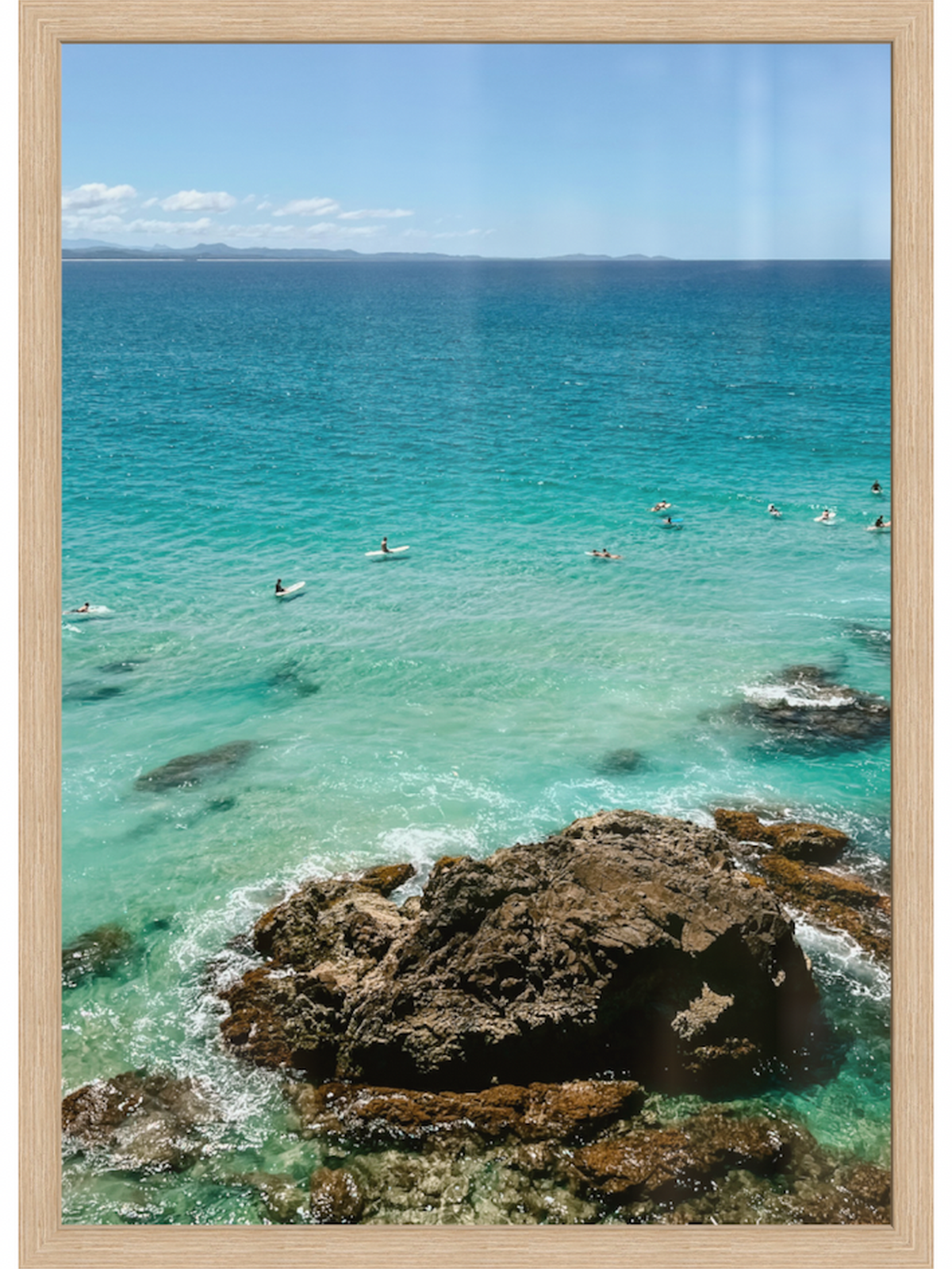 Beach scene with clear blue water, rocks, and people swimming.
