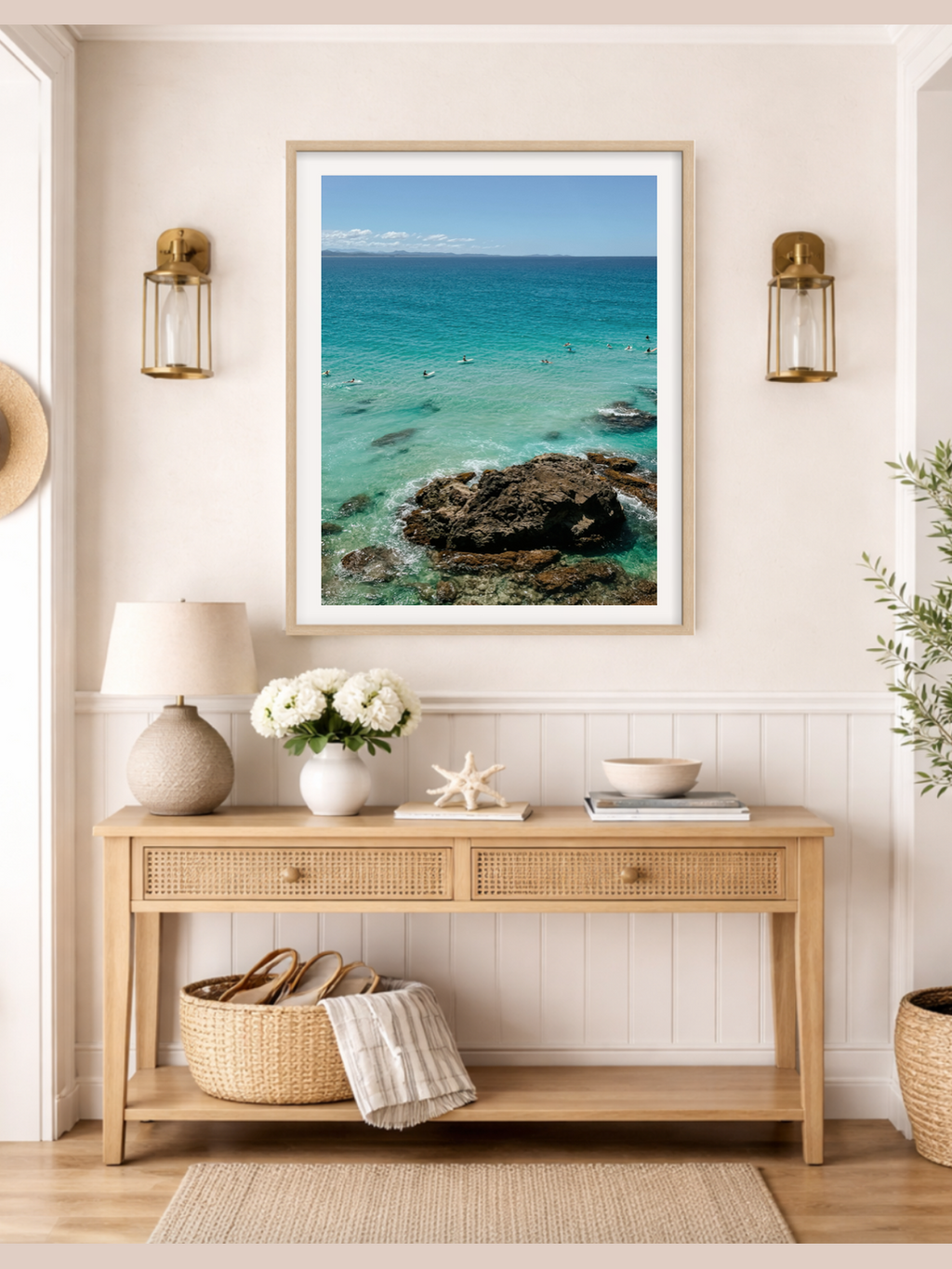 Framed artwork of a coastal scene above a wooden console table in a room.