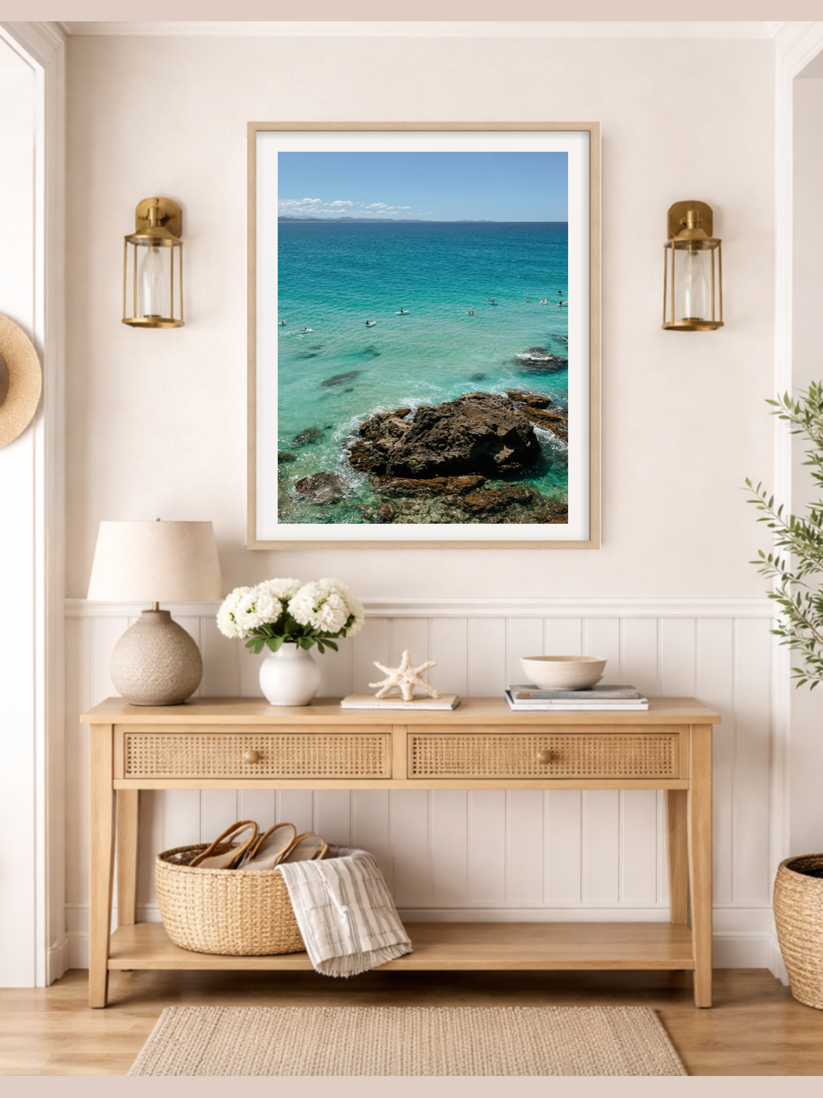 Framed artwork of a coastal scene above a wooden console table in a room.