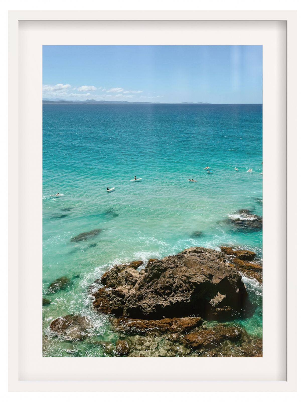 Framed photograph of a coastal scene with clear blue water and rocks.