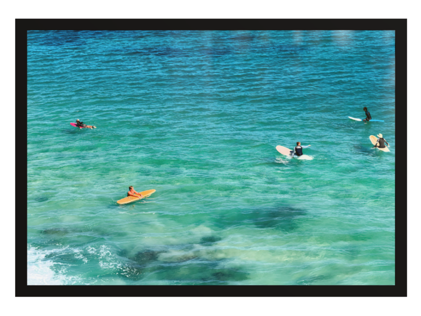 People on surfboards and a kayak in clear blue water
