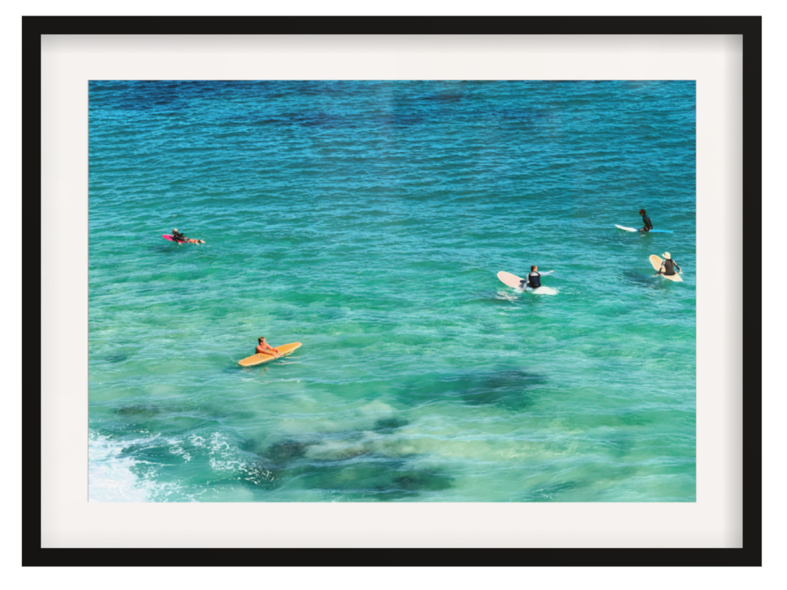 People on surfboards in clear blue water with a black frame.