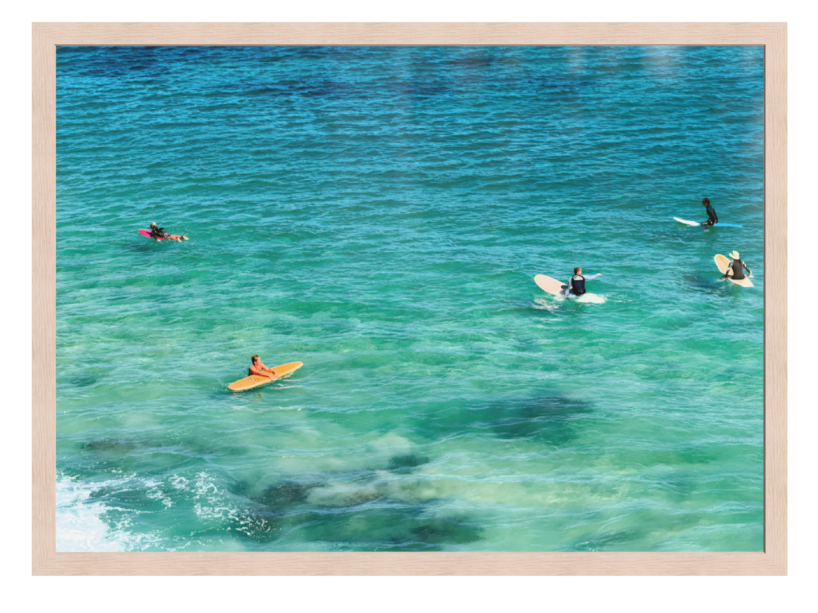 People swimming and surfing in clear blue water with a wooden frame.
