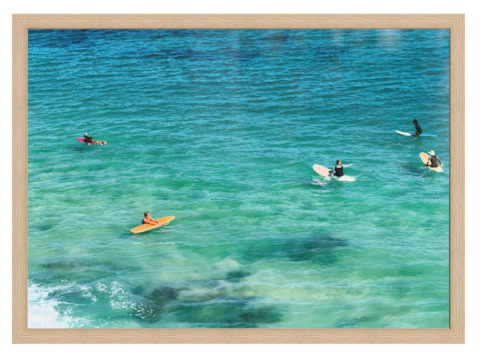 People on surfboards and in kayaks in clear blue water with a wooden frame.