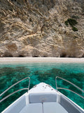 Boat approaching a rocky beach with clear blue water