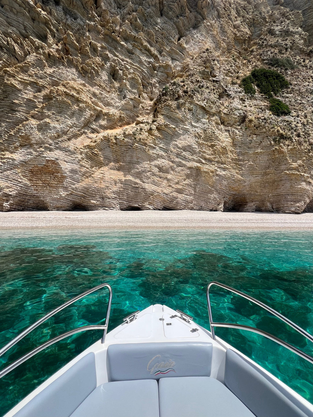 Boat approaching a rocky beach with clear blue water