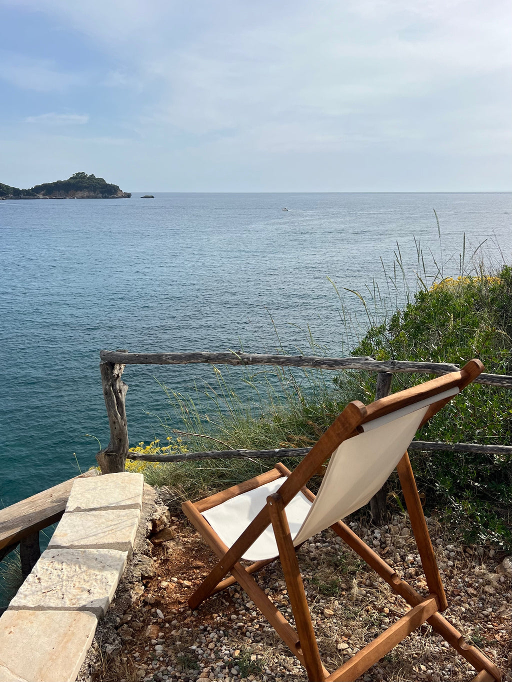 Wooden chair with white cushion facing the ocean