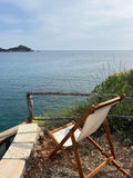 Wooden chair with white cushion facing the ocean